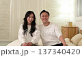 Japanese couple sitting on bed and looking at camera 137340420