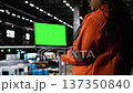 Green screen laptop held by black woman engineer in industrial factory, large-scale manufacturing process. Heavy industry plant with steel beams, mechanical systems and heavy machinery. 137350840