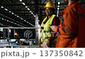 Portrait of black woman working in heavy industry engineering plant, wearing helmet and handling metalwork in large-scale machinery for production line. Manufacturing process in factory. 137350842