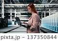 Optimizing electronics, laptop and woman in server farm doing improvements. Monitoring system performance, notebook and female technician walking in data center, identifying bottlenecks, camera A 137350844