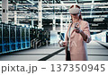 Data center female engineer uses VR glasses to manage enterprise cloud computing IT solutions. Software developer using virtual reality simulation to monitor server farm facility workspace, camera A 137350945