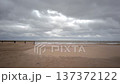Wide view of an empty beach on a stormy autumn day. Dark clouds move across the sky while strong winds push rough waves toward the shoreline.  137372122
