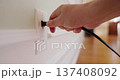 Hand plugging and unplugging electric plug into wall outlet 137408092