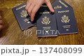 Hands taking United States passports one by one from table, concept of travel, immigration or citizenship 137408099
