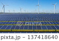 Aerial view of massive solar panel farm with wind turbines generating renewable energy under clear blue sky 137418640