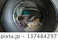 Laundry rotating inside washing machine drum during active wash cycle in modern household appliance 137484297