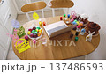 A wooden table is set up for Easter egg decorating with painted eggs, cakes, and art supplies 137486593