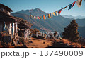 Colorful prayer flags wave over a mountain village in the afternoon sun with green hills in the background 137490009