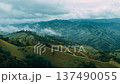 Mountain landscape showing hills, trees, and clouds in a rural area during daytime 137490055