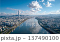 City skyline view along the river with tall buildings and mountains under a blue sky in Seoul at midday 137490100