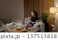 Woman sitting on sofa and eating snack while watching laptop 137513818
