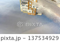 Reflection of an apartment building in a frozen puddle, winter thaw in the city, icy surface of the city and abstract background of a residential building. 137534929