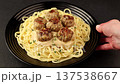 Swedish noisettes (fricandel) with spaghetti and Brune Sos creamy sauce. Traditional meatballs with garnish. Woman turning a plate. Selective focus, close-up. 137538667