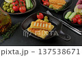 Grilled halloumi cheese in a black pan with olives, tomatoes, cucumbers, thyme and lemon. Traditional cheese of the Eastern Mediterranean. A man puts a lemon on a plate. Selective focus. 137538671