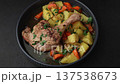 Duck leg with broth, stewed with potatoes and carrots, sprinkled with parsley and sumac. Simple home hearty cooking. Deep gray plate on a black background. Camera zoom. Selective focus, close-up. 137538673