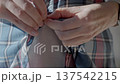 Closeup of woman hands unbuttoning button on plaid shirt 137542215
