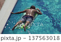 Man is sunbathing while floating on inflatable air mattress in swimming pool, vacation, enjoying summer day relaxation and leisurely activity outdoors, body immersed in refreshing blue water 137563018
