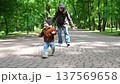 Toddler running on park path with parent following 137569658