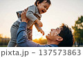 Asian father playing with happy toddler son during golden hour sunset in outdoor park setting 137573863