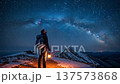 Mountain hiker with lantern observing spectacular milky way galaxy over snow covered winter landscape at night 137573868