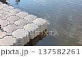 Modular plastic pontoon is floating on water. Small ripples appear as the water moves around the pontoon. It is daytime and the sun is shining 137582261