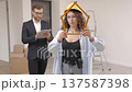 Businessman is holding a tablet and looking at the modeling of an apartment, while a designer is standing with a ruler in her hands and looking at the camera 137587398