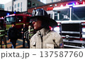 Fire station. A firefighter stands next to a fire engine. Fire trucks, their lights on, are ready to go. Realistic 4k animation. 137587760