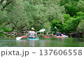 Family and solo traveler paddling kayaks on river during summer slow motion expedition connecting with nature, outdoor adventure, water tourism, slow river journey 137606558