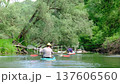 Family and solo traveler paddling kayaks on river during summer slow motion expedition connecting with nature, outdoor adventure, water tourism, slow river journey 137606560
