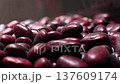 Close-up view of dark red kidney beans piled together, showcasing their smooth surfaces and varied shapes in a natural setting with soft lighting and contrasting background 137609174