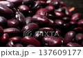 Close-up view of dark red kidney beans piled together, showcasing their smooth surfaces and varied shapes in a natural setting with soft lighting and contrasting background 137609177