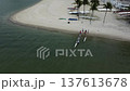 People on a white sanded tropical beach preparing an outrigger canoe for a trip 137613678
