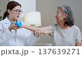 Asian physiotherapist helping senior patient with dumbbell exercise. 137639271