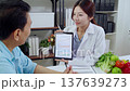 Asian nutritionist showing AI health analysis graph on tablet to man patient. 137639273