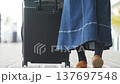 A woman's feet as she walks with a suitcase in front of the airport terminal. (Image of a travel departure) A woman's feet as she walks with a suitcase in front of the airport terminal. (Image of a travel departure) 137697548