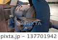 Worker uses grinding machine in workshop to sharpen metal tools during afternoon hours in home garage setting 137701942