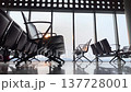 Airport seating area features modern chairs in rows, large windows showcasing a cloudy sky and distant mountains, enhancing the spacious ambiance 137728001