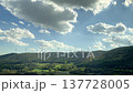 Wind turbines spin on green hills under a vibrant sky, illustrating the integration of renewable energy into the natural environment 137728005