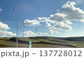 Wind turbines spin gracefully on hills, surrounded by lush greenery and open fields, illustrating the beauty of renewable energy in a serene rural setting 137728012