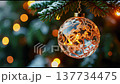 Sparkling Christmas ornaments dangle from green pine branches, glowing softly with warm lights during a peaceful winter evening. A celebration of holiday cheer. 137734475