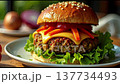 Enjoy the process of making a tasty homemade burger featuring a fluffy sesame bun, fresh lettuce, juicy toppings, and melted cheese. Cooking takes place in a warm kitchen filled with ingredients. 137734493