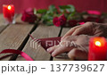 Man Hand Putting Valentine Card in Red Envelope with Roses and Candles Close Up 137739627