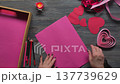 A woman's hand draws hearts on pink cardboard for Valentine's Day. 137739629