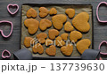 Placing baking tray with baked heart shaped gingerbread cookies 137739630