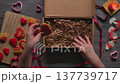 Women Hands Placing Red Iced Gingerbread Hearts in Kraft Gift Box Top View 137739717