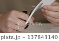 Scissors Cutting Paper Strip in Hands Close Up 137843140
