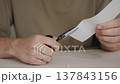 Hands Cutting Paper with Scissors on Table 137843156