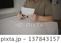 Man Continues Cutting White Paper with Scissors 137843157