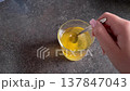 Stirring hot tea in glass cup with metal spoon creating gentle liquid swirl relaxing beverage preparation closeup warm drink infusion morning routine comfort concept 137847043