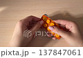 Pressing medicine tablet from blister pack and dropping pill onto wooden table closeup pharmaceutical dosage healthcare treatment concept pharmacy medication routine 137847061
